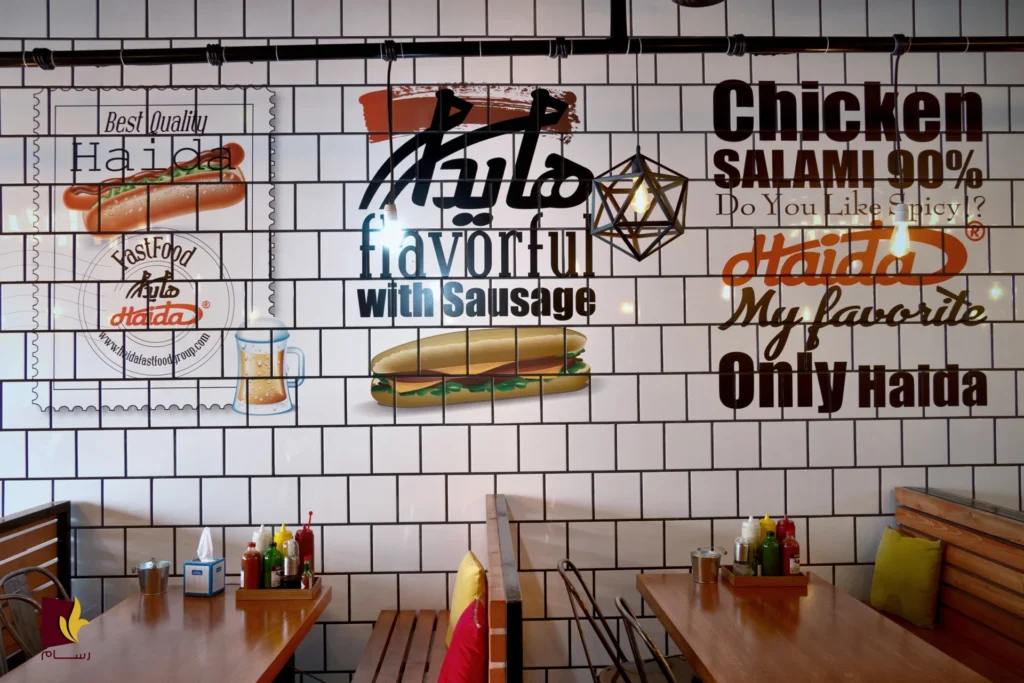 Innenraum eines Haida Fast-Food-Restaurants mit Wandgrafiken, Hotdog- und Sandwich-Illustrationen sowie Holztischen